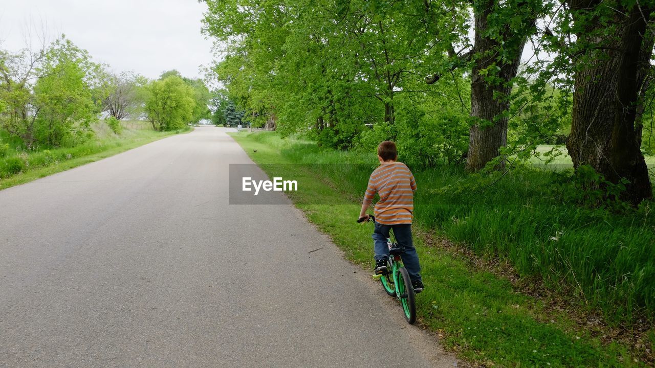 Rear view of boy riding bike