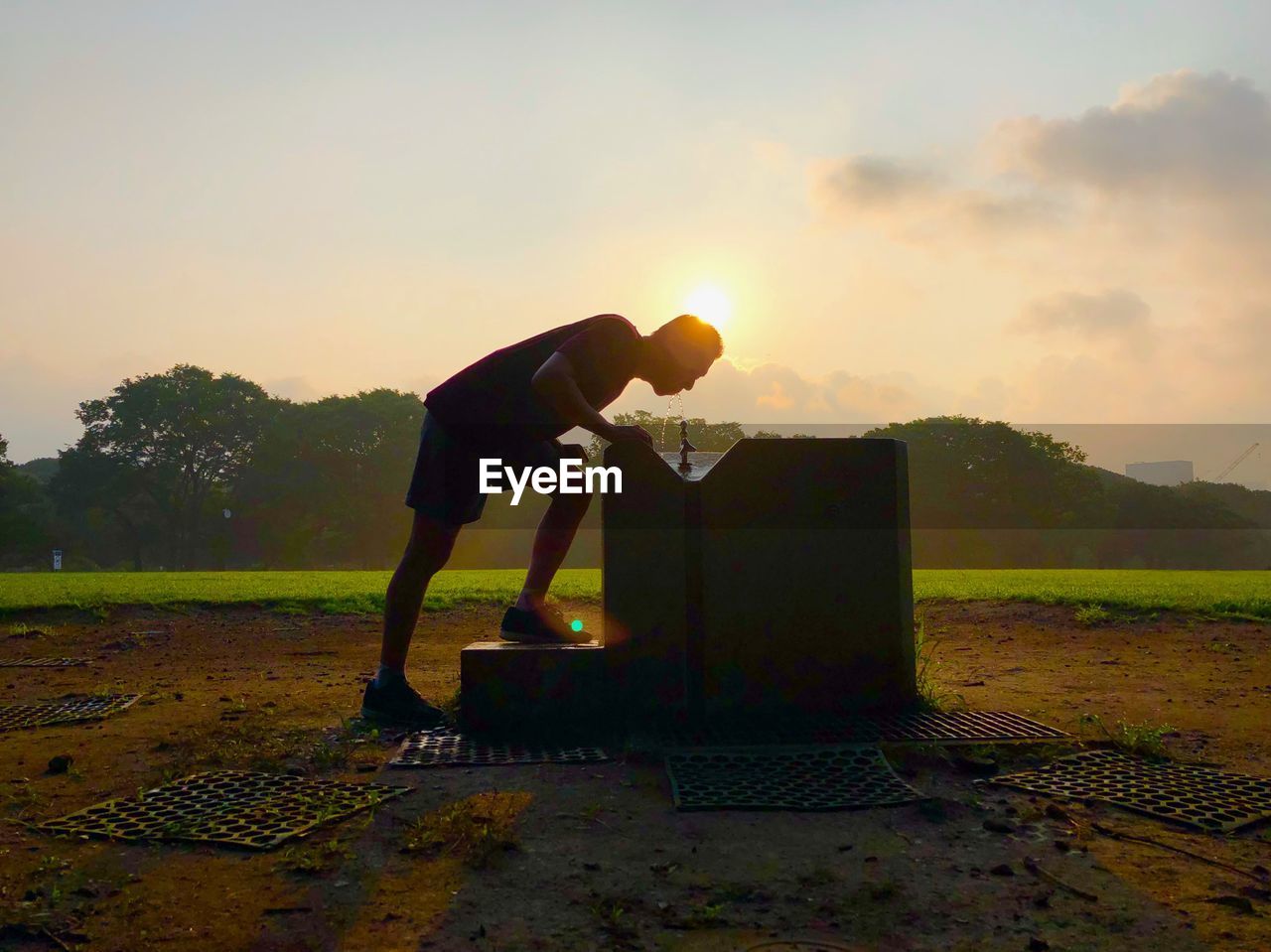 SIDE VIEW OF MAN STANDING ON FIELD AGAINST SKY