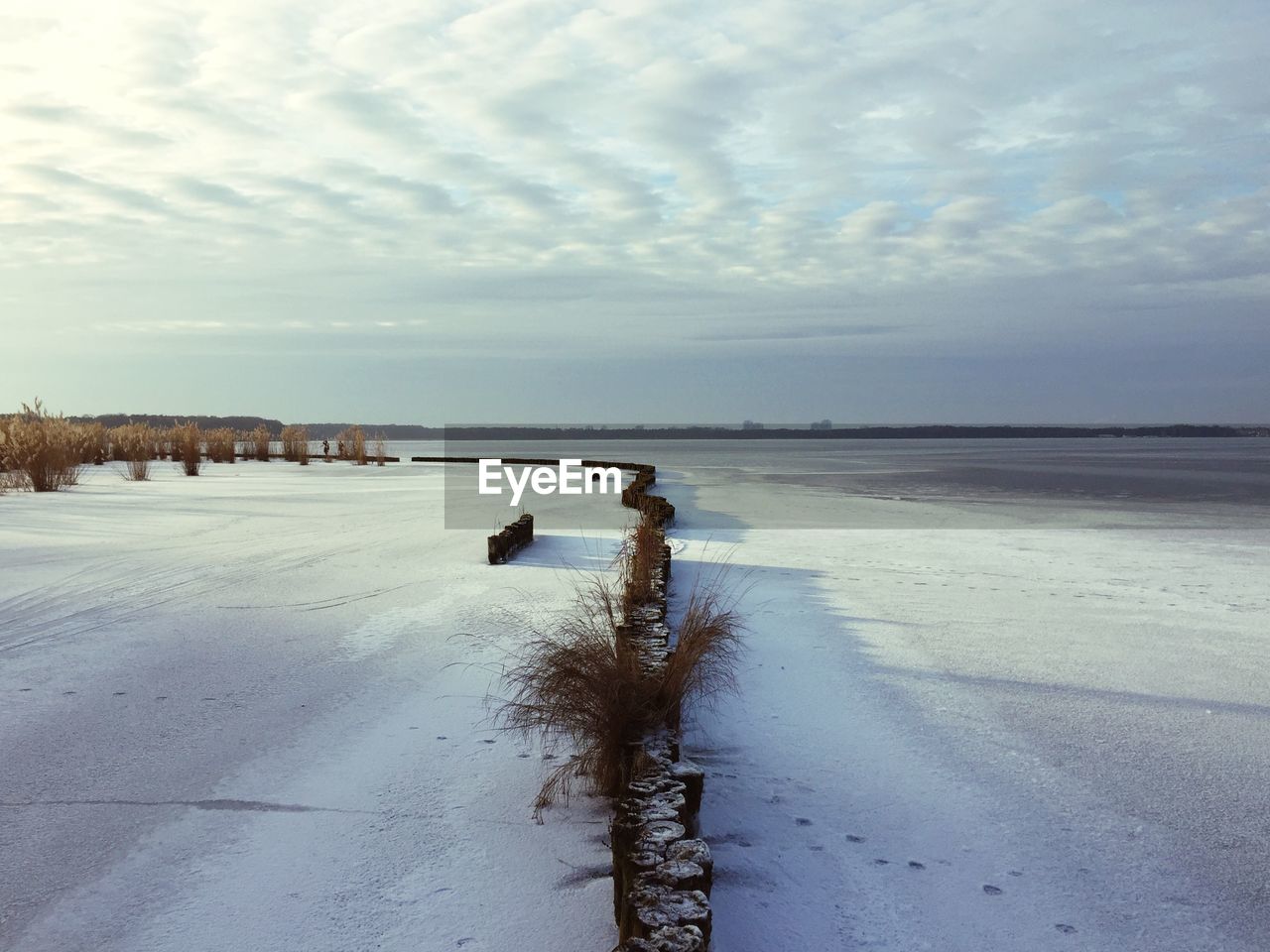 Scenic view of frozen beach against sky