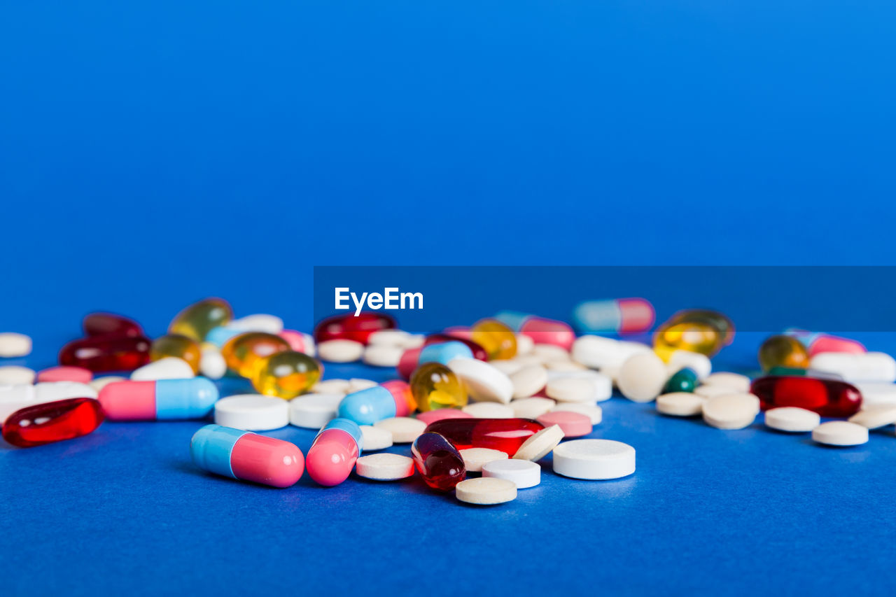 high angle view of pills spilling on blue background