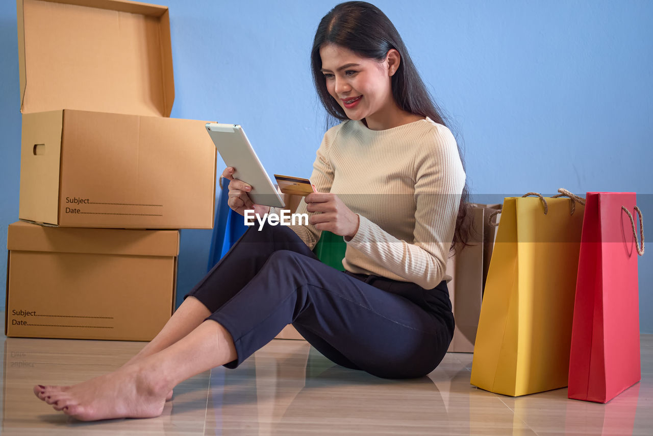 YOUNG WOMAN SMILING WHILE SITTING ON SOFA