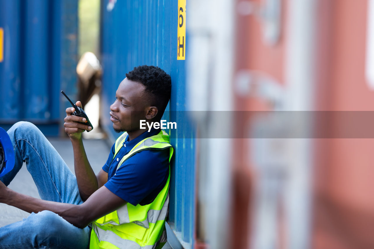 Side view of a young man talking on walkie-talkie at warehouse