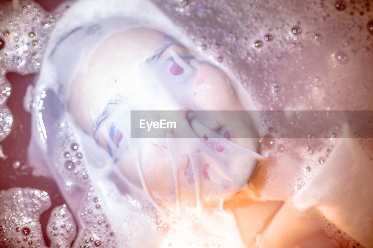 Close-up of young woman with face covered by textile in bathtub