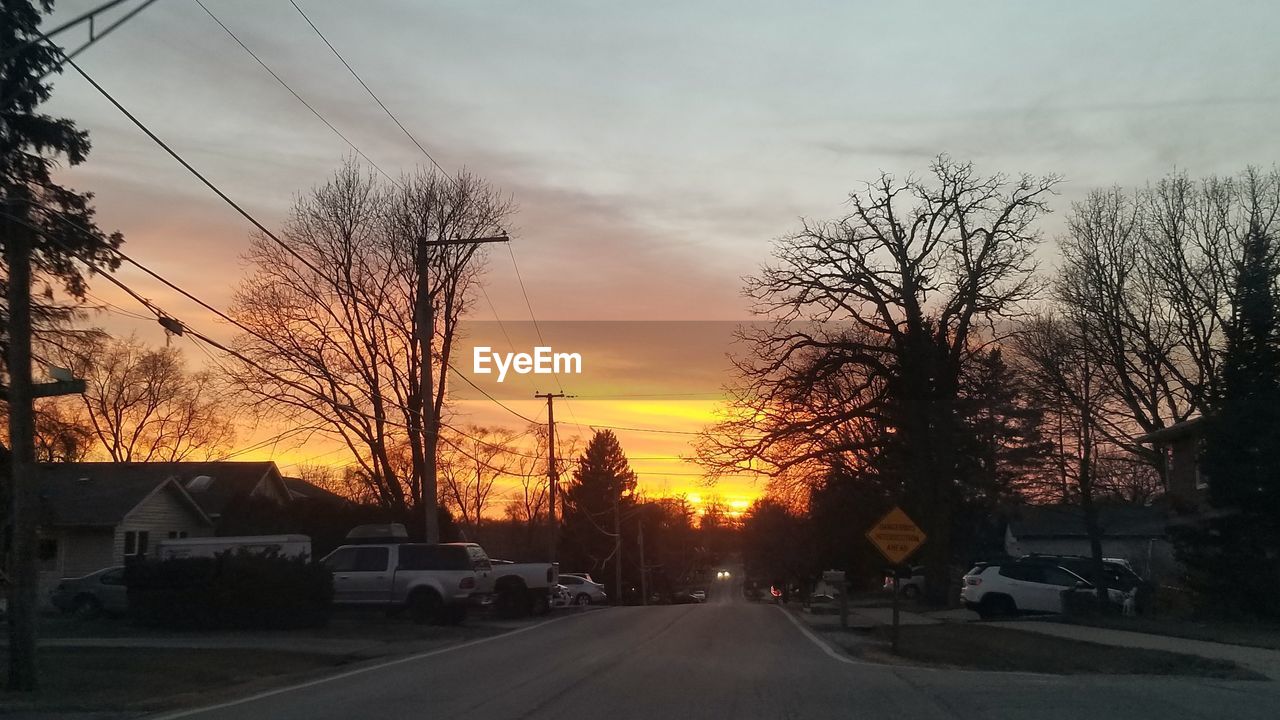 CARS ON STREET AGAINST SKY DURING SUNSET