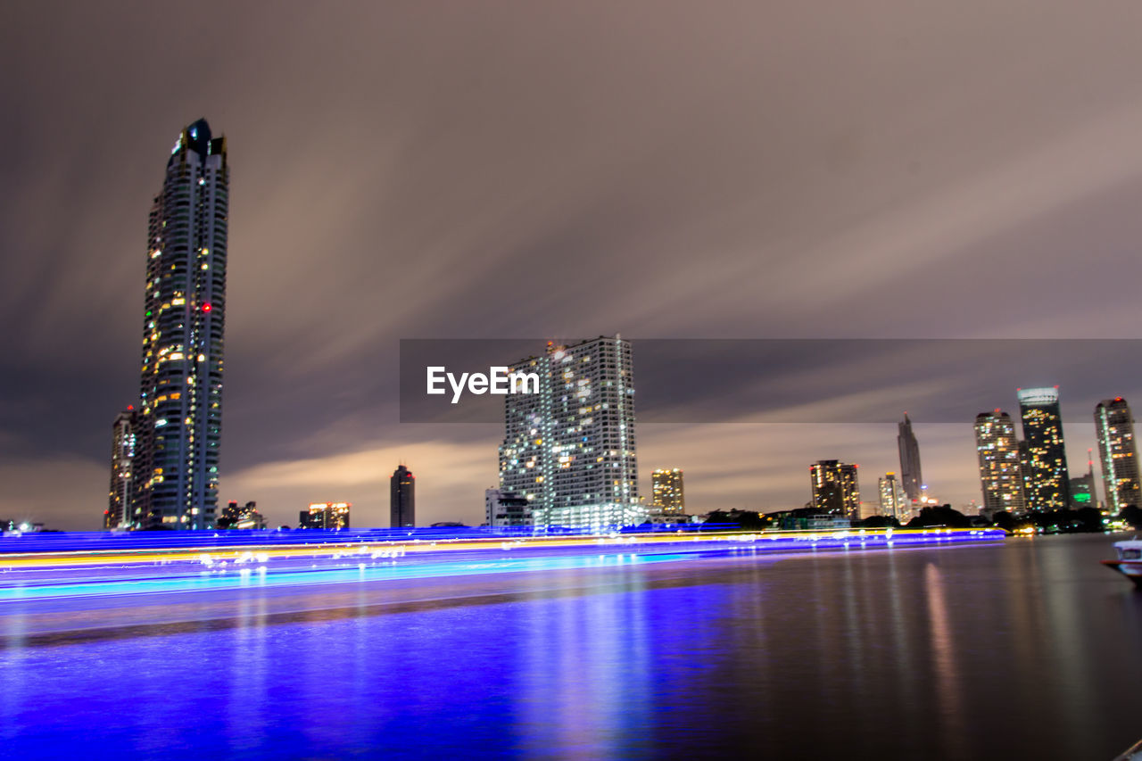 Illuminated modern buildings in city against sky at night