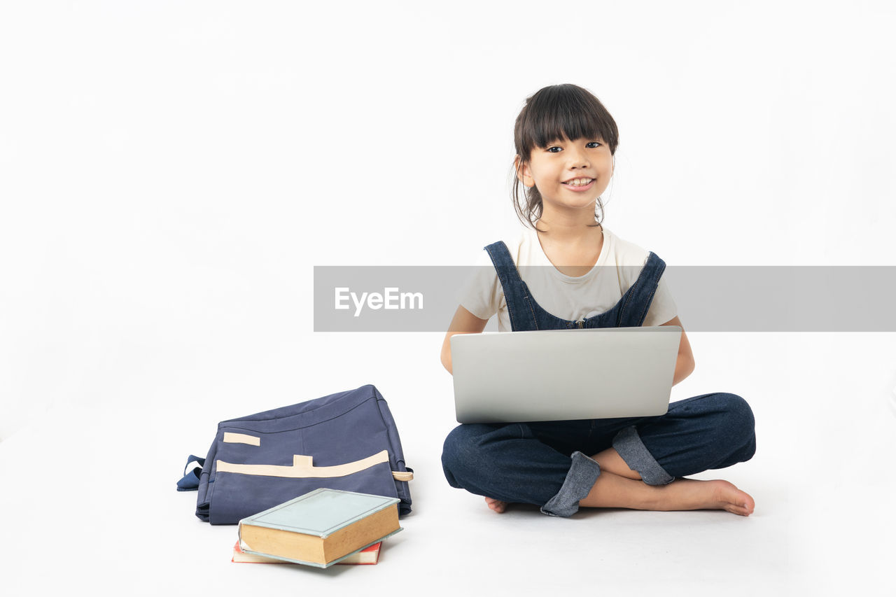 SMILING YOUNG WOMAN USING LAPTOP ON WHITE