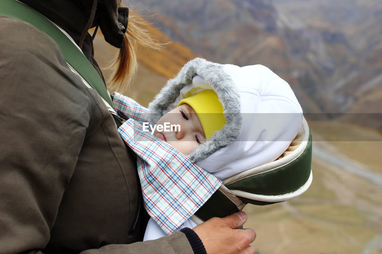 Midsection of woman standing with baby on mountains