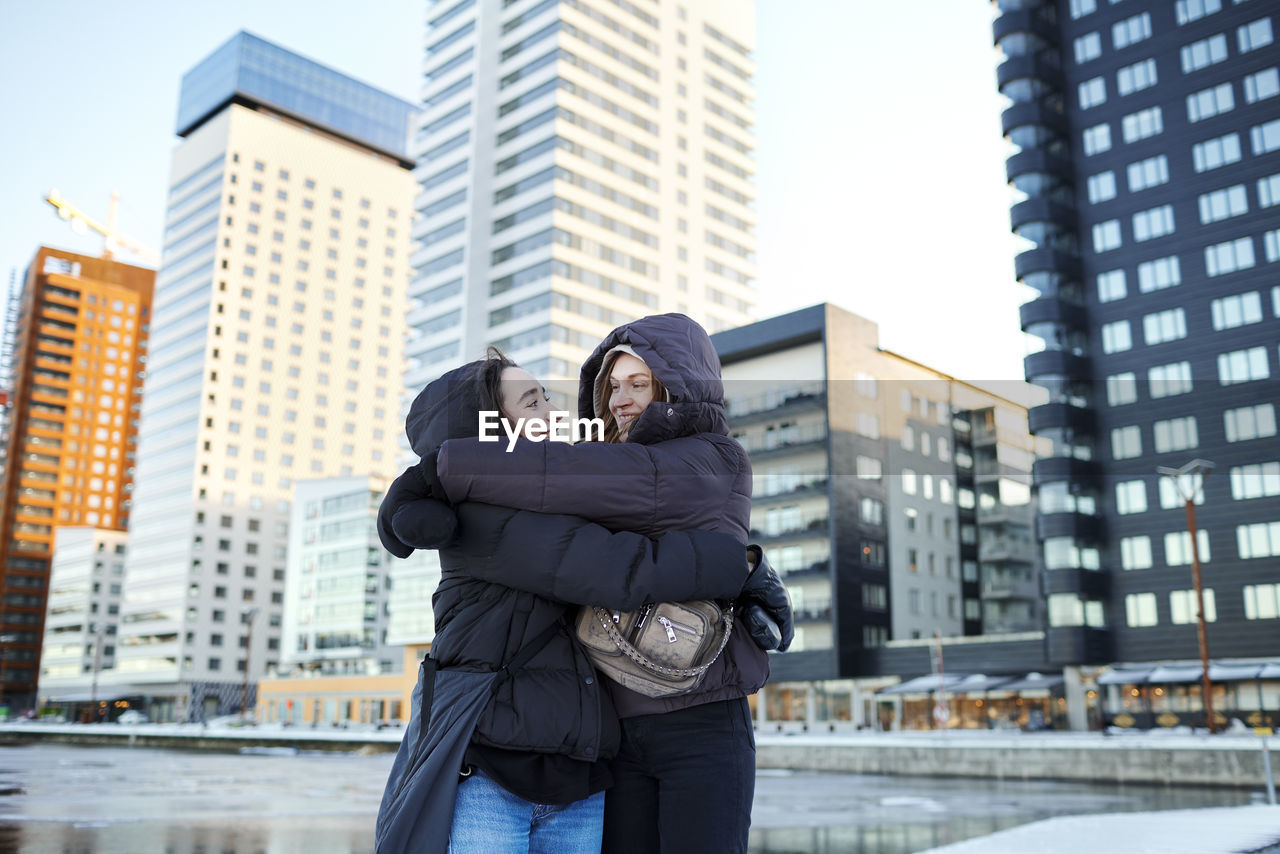 Young female couple hugging in modern neighborhood