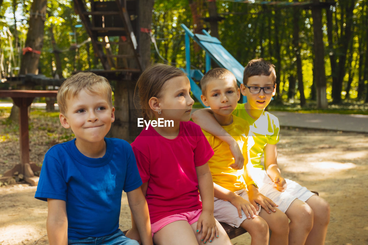 portrait of smiling friends sitting on field at park