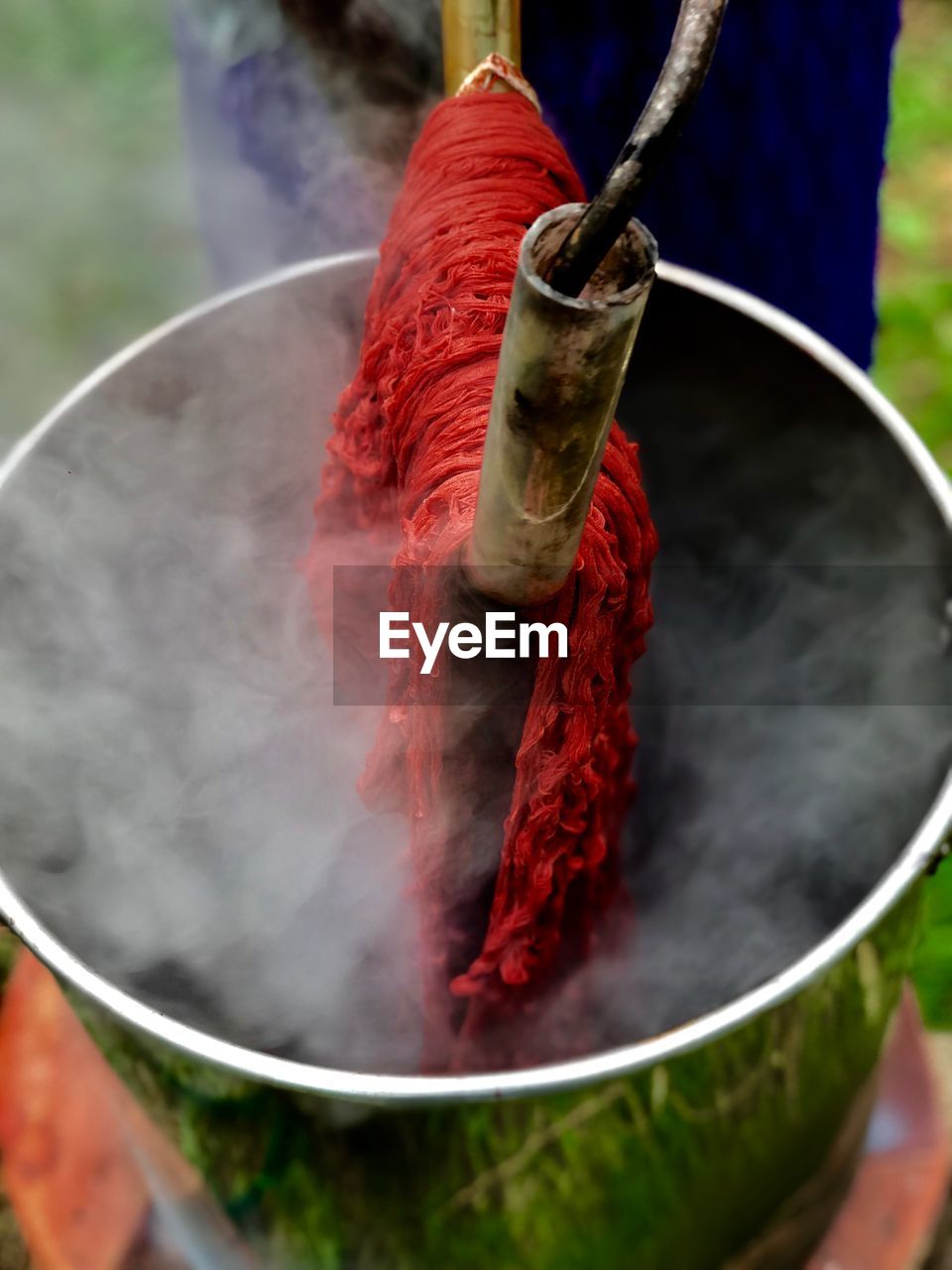 Close-up of red fabric hanging over container emitting steam