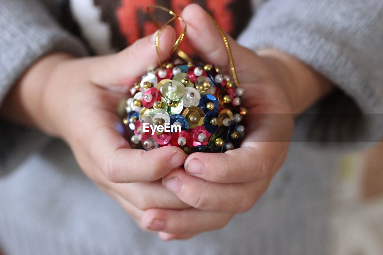 Midsection of person holding multi colored decoration