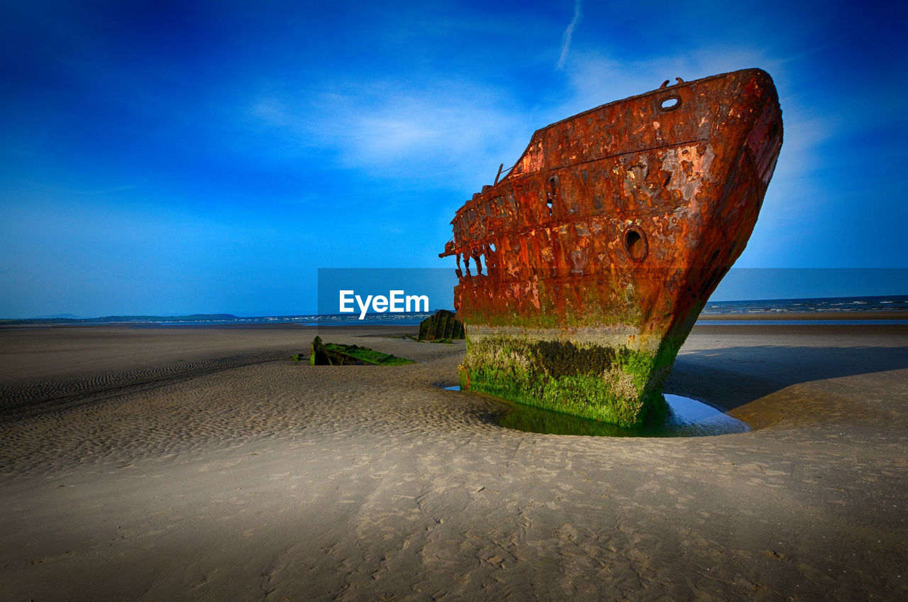 Abandoned shipwreck on beach against sky