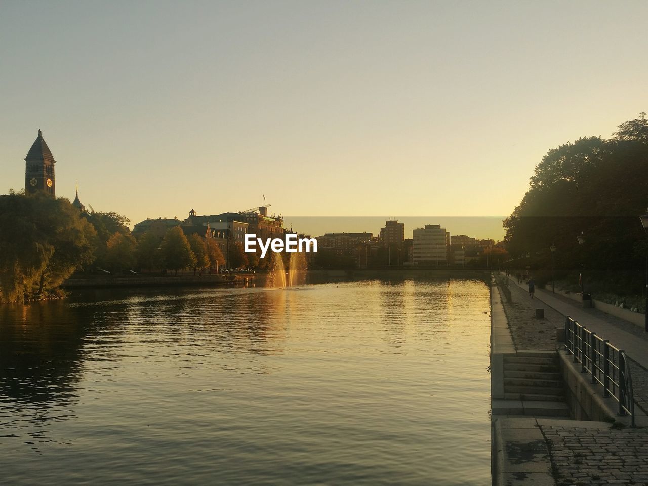 BUILDINGS BY RIVER AGAINST CLEAR SKY