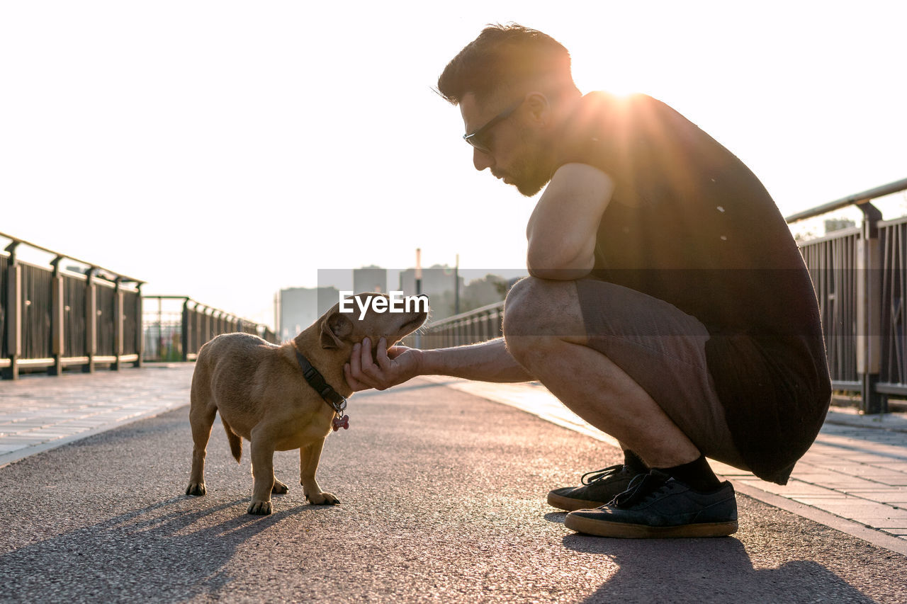 Young handsome man is walking with his dog in the morning on empty street of city.