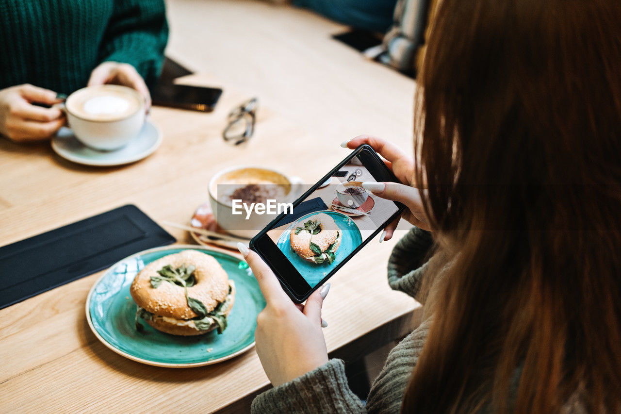 Rear view of woman using mobile phone on table