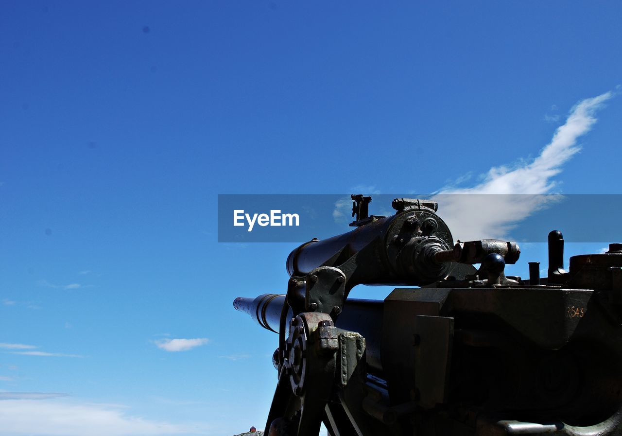 Low angle view of cannon against blue sky