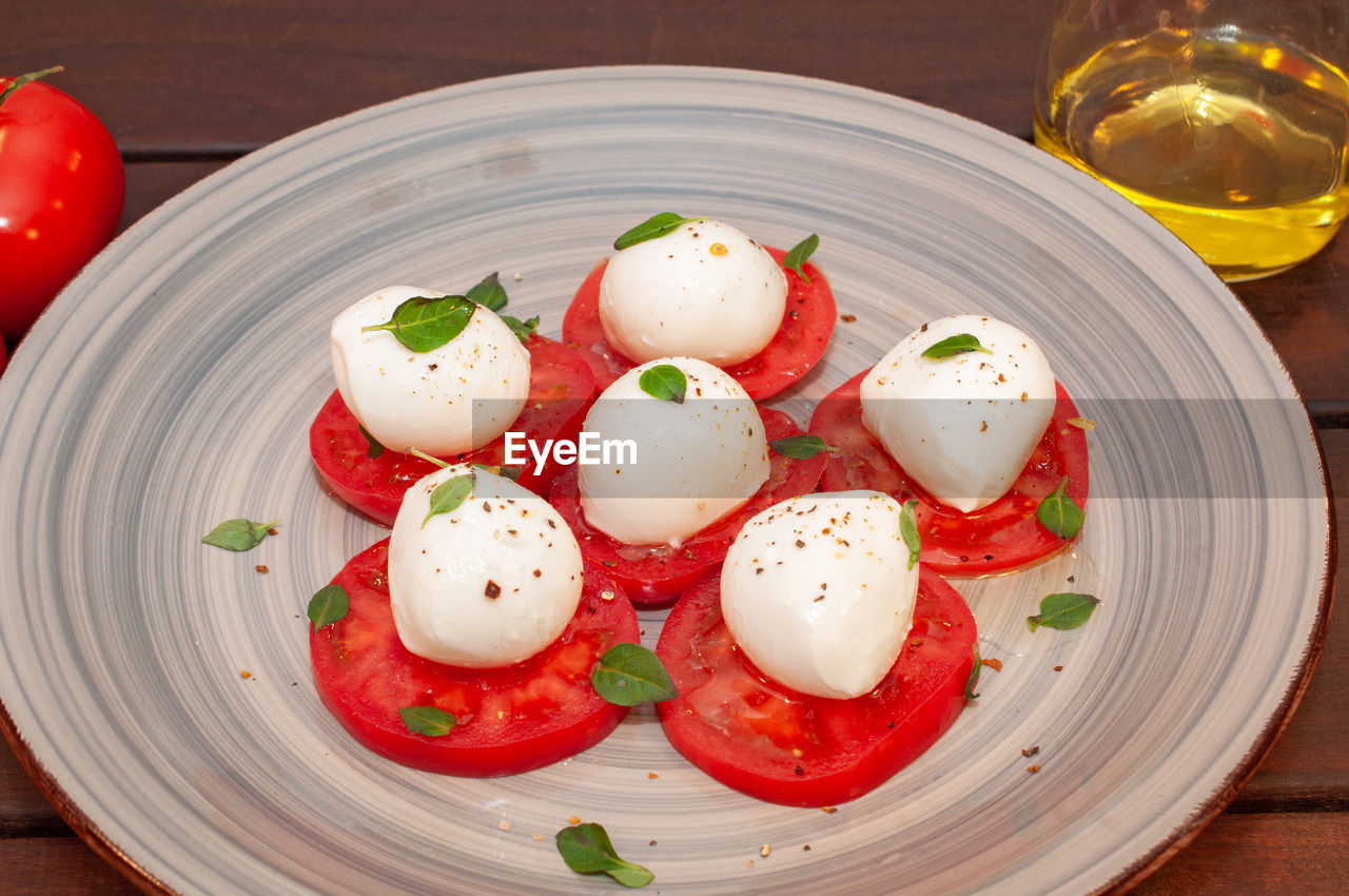 food and drink, food, healthy eating, vegetable, freshness, dish, produce, tomato, wellbeing, caprese salad, meal, plate, mozzarella, no people, wood, fruit, table, red, cuisine, egg, seasoning, indoors, herb, still life, appetizer, close-up, pepper - seasoning, cherry tomato
