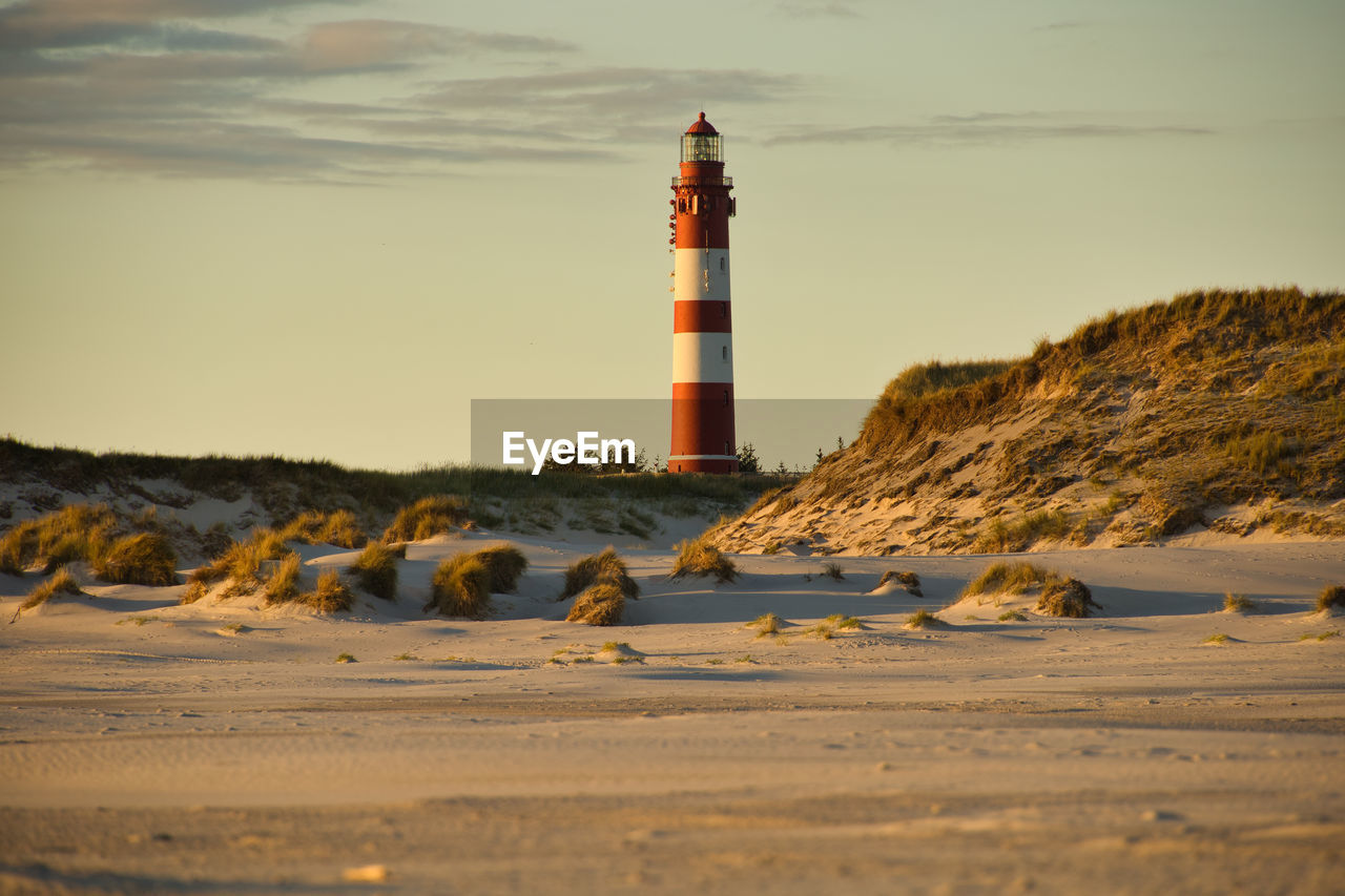 Lighthouse on beach against sky