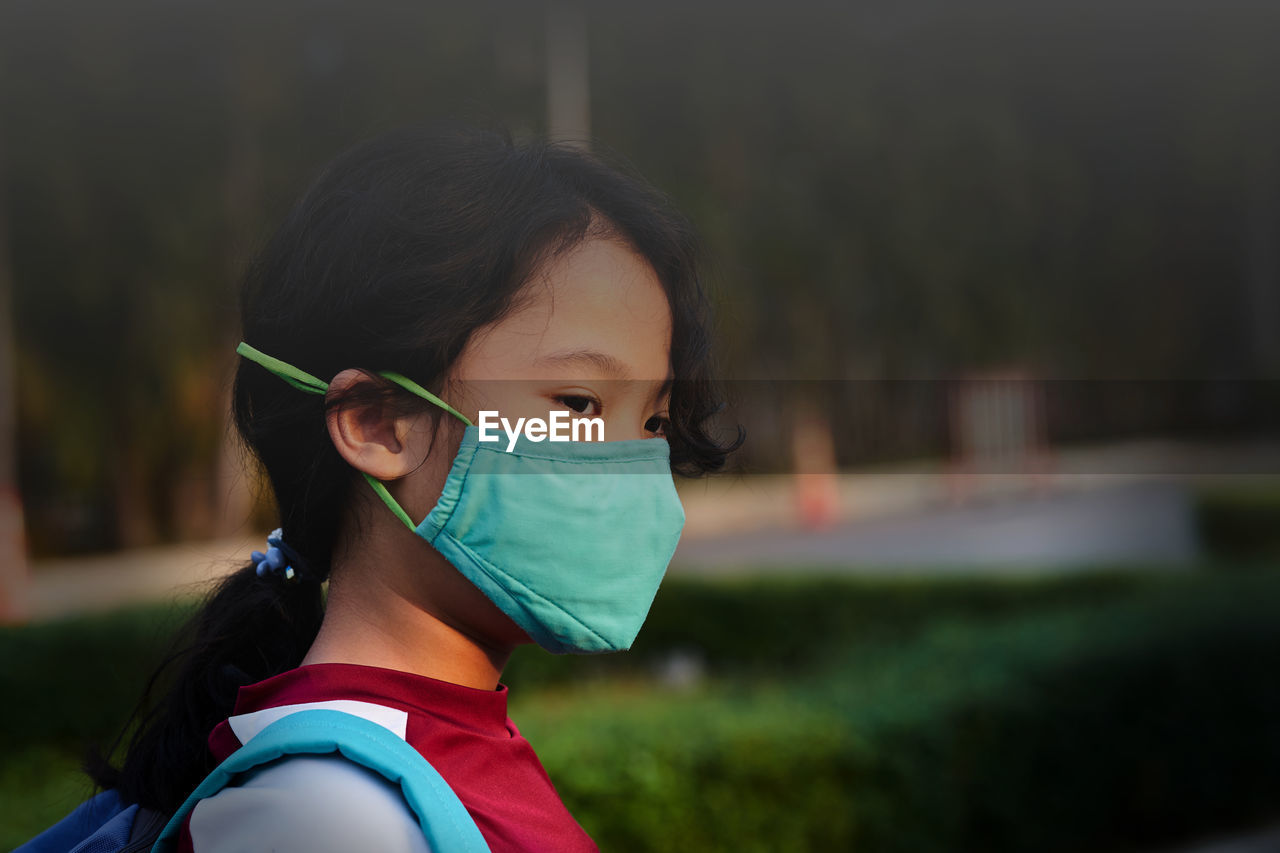 Girl with n95 mask protection from pm 2.5 dust crisis at school in pollution concept