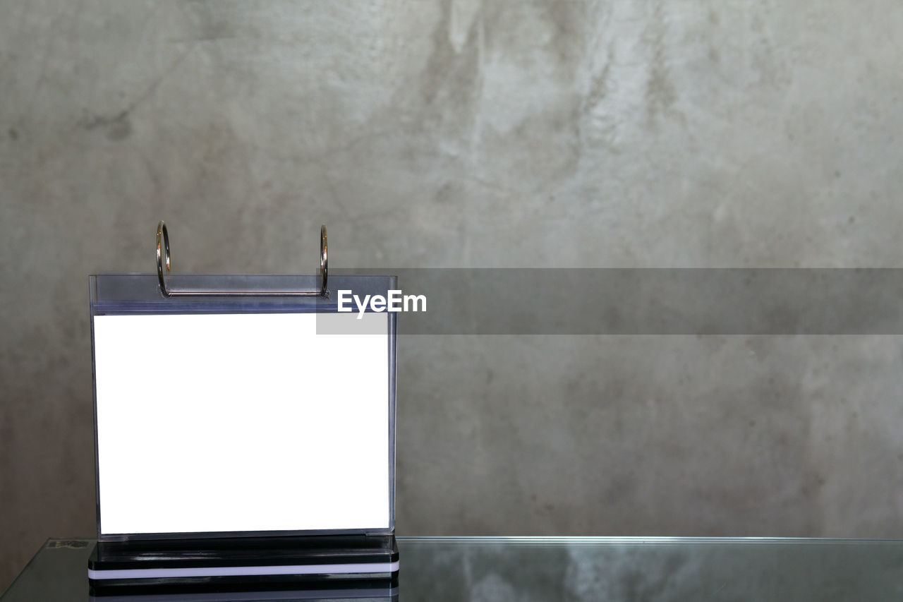 CLOSE-UP OF WHITE WALL WITH TEXT ON TABLE