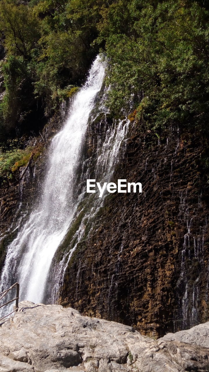 SCENIC VIEW OF WATERFALL AGAINST ROCKS