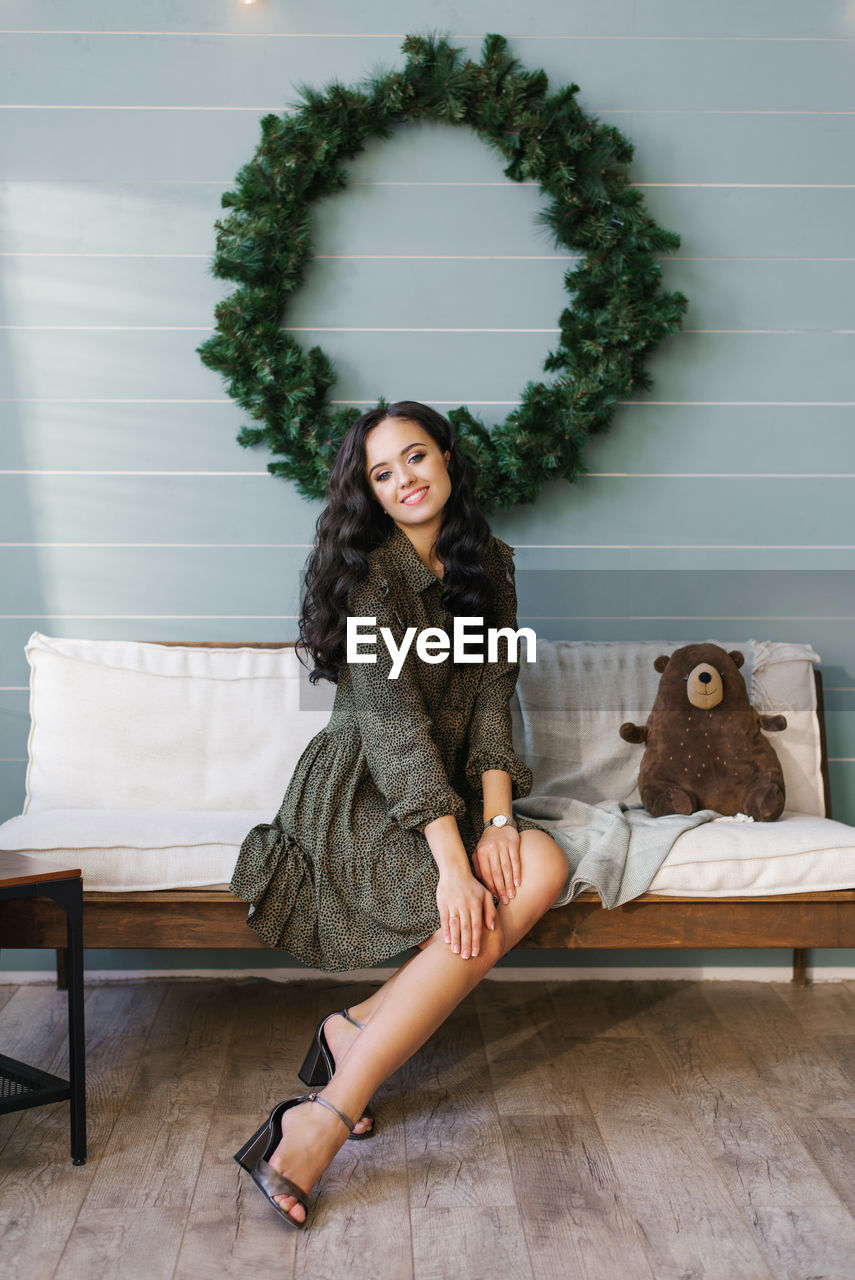 A cute young woman in a joyful mood is ready to celebrate christmas and new year, sitting 