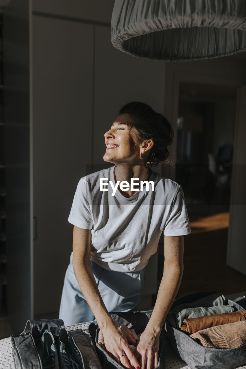 Woman folding clothes in bedroom