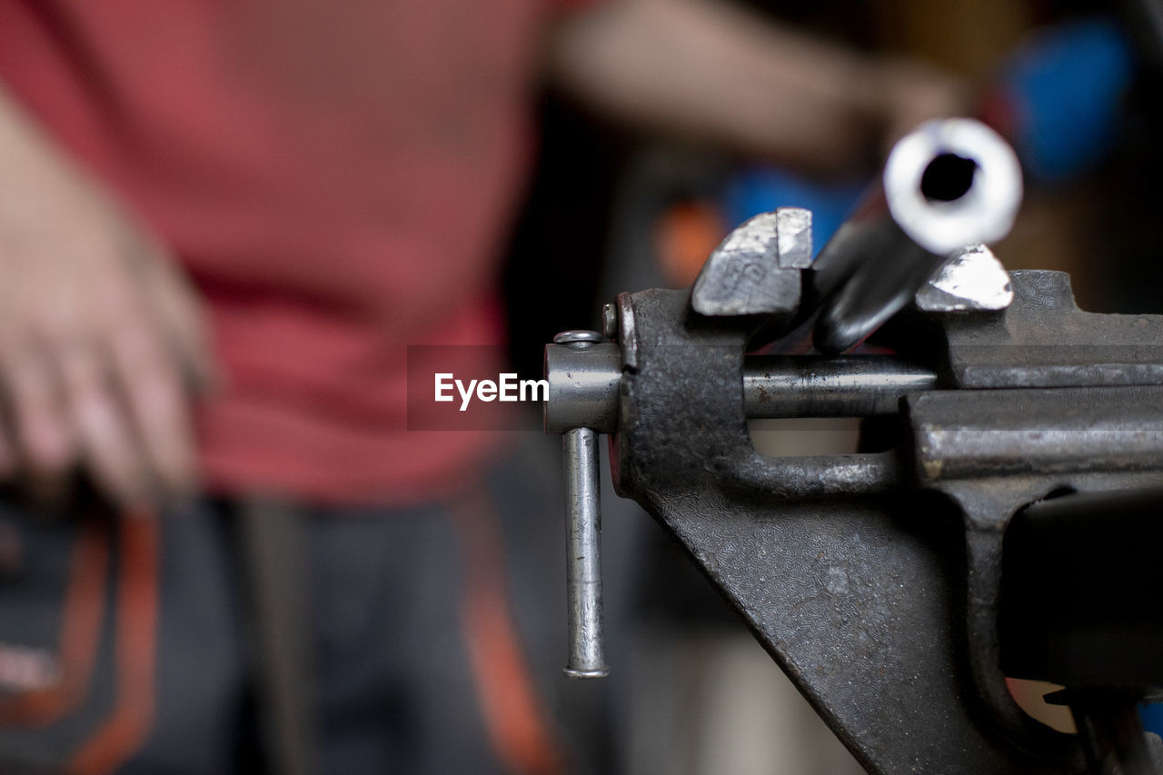 CLOSE-UP OF PERSON WORKING IN METAL MACHINE