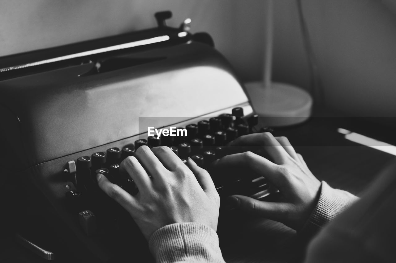 Cropped hand of person typing on typewriter