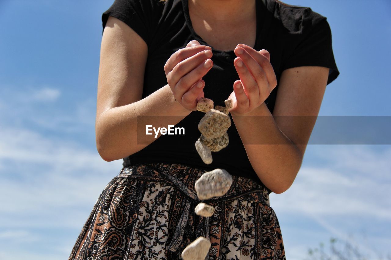 Midsection of woman dropping stones