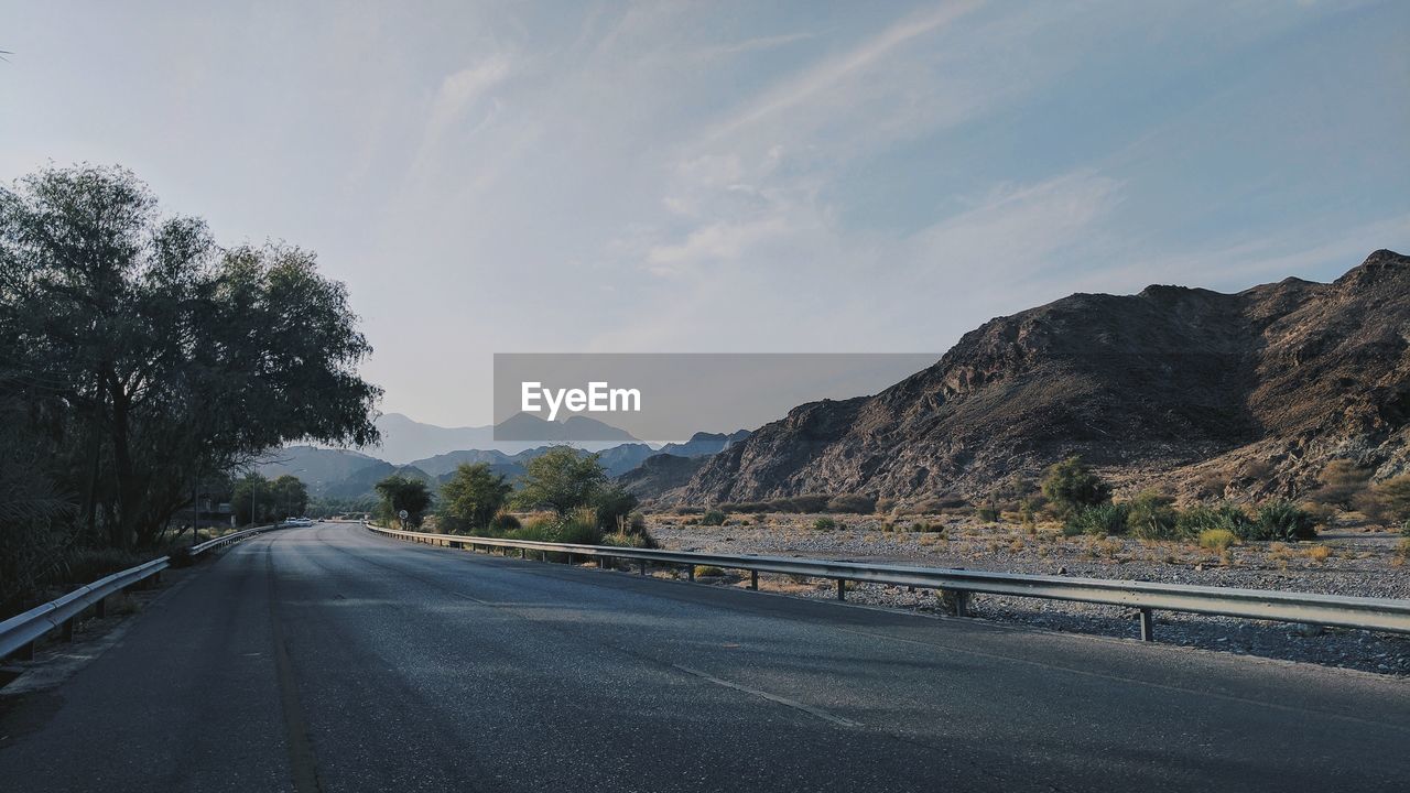 SURFACE LEVEL OF ROAD BY TREES AGAINST SKY