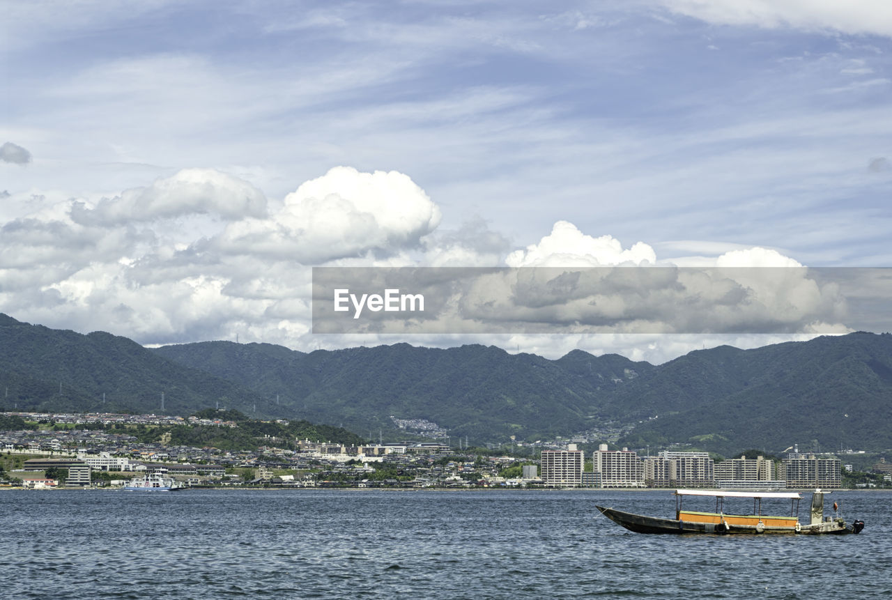 BOATS IN SEA AGAINST MOUNTAINS