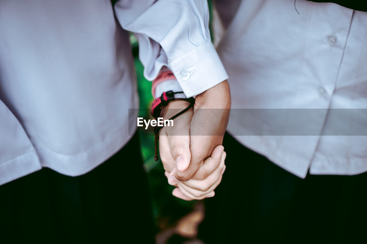 Midsection of couple holding hands