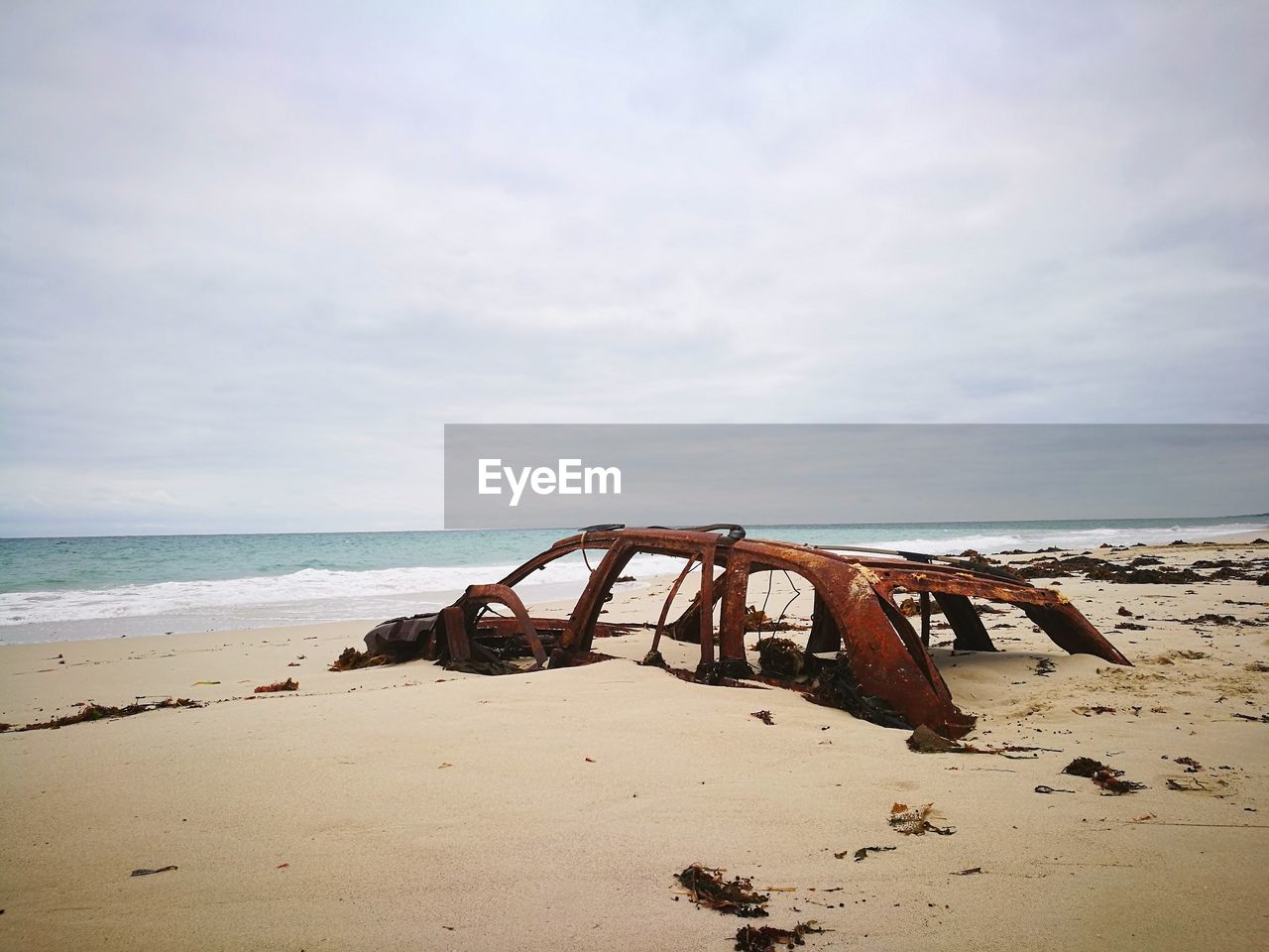 Abandoned rusty on beach against sky