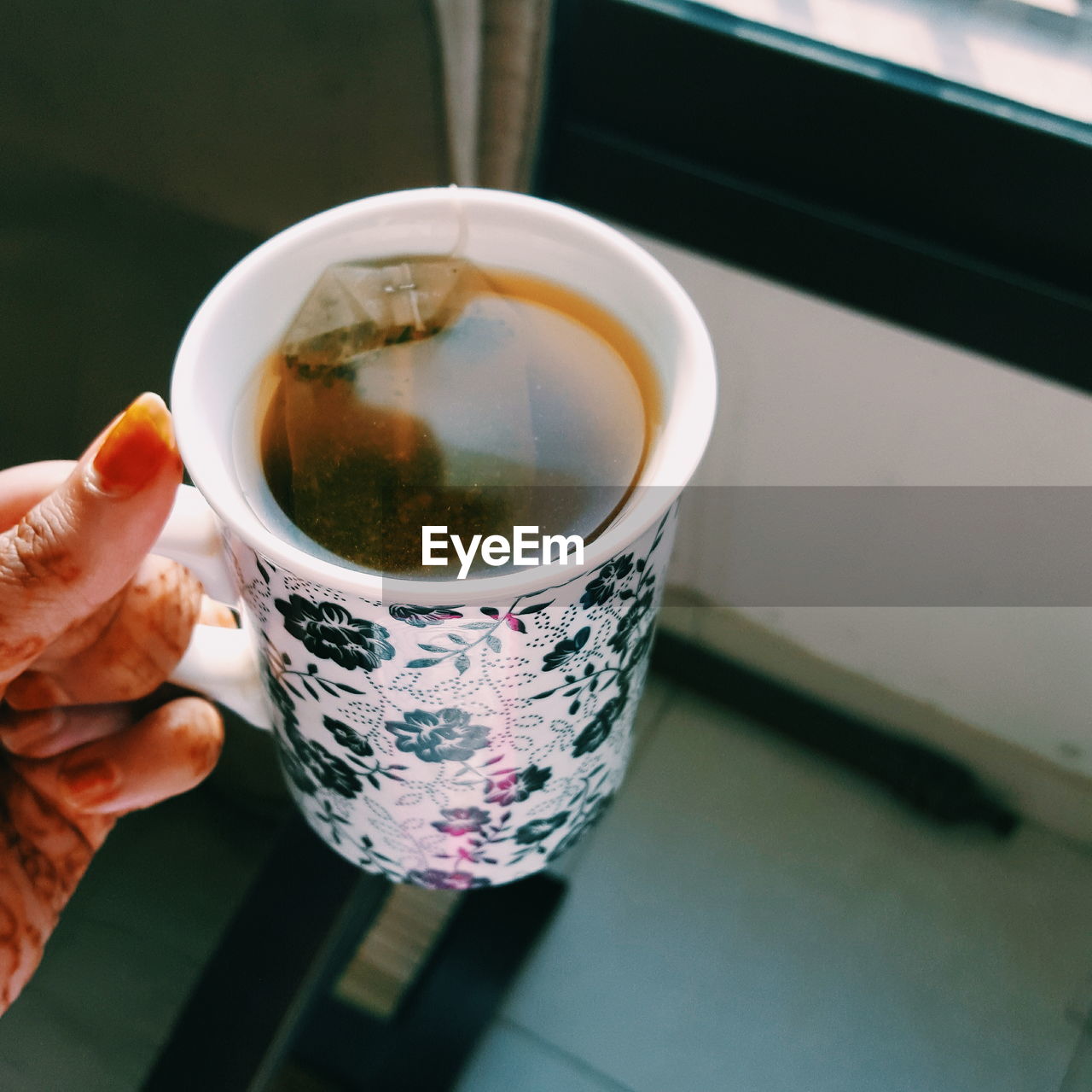 Cropped hand of woman holding tea cup at home