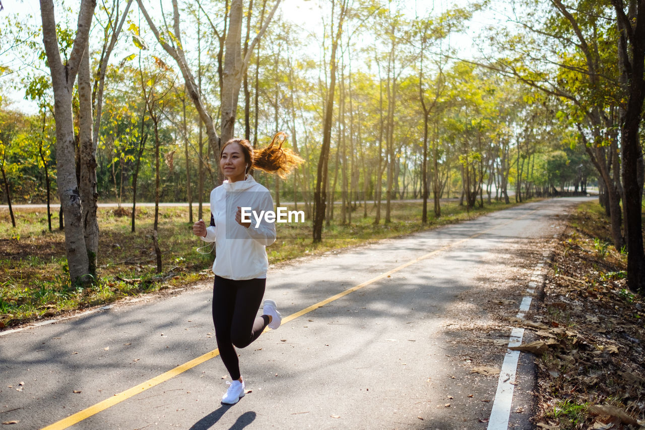 Smiling woman jogging on road