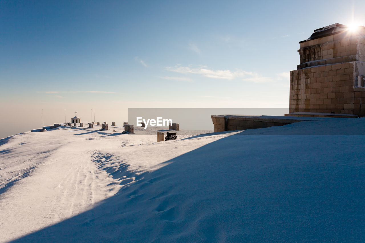 SNOW COVERED LAND AND BUILDINGS AGAINST SKY