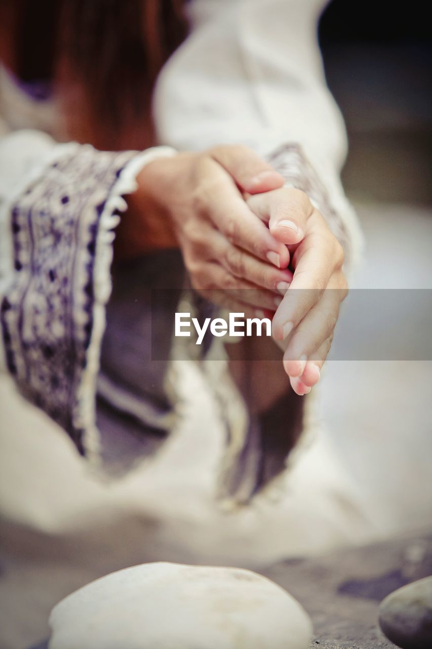 Close-up of woman rubbing hands over dough at kitchen counter