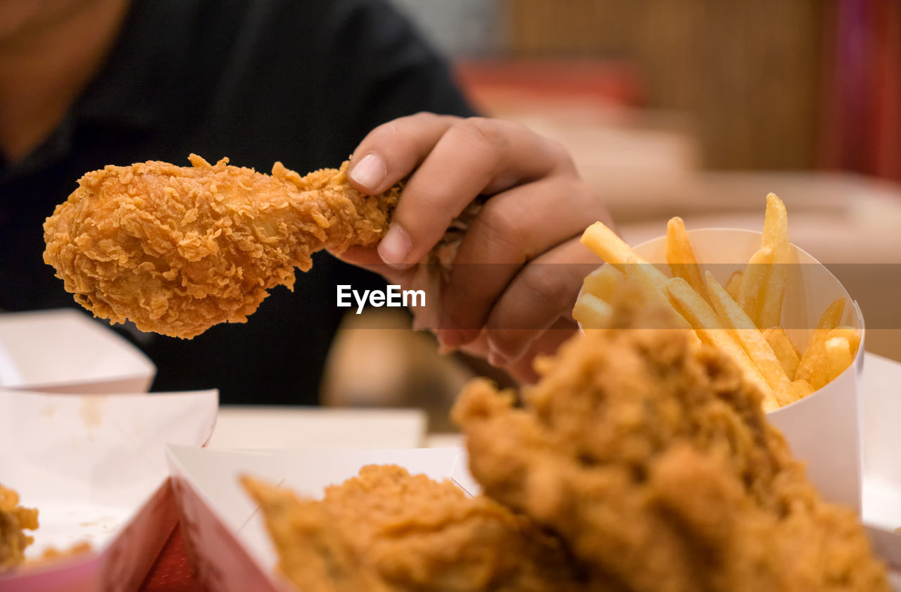 CLOSE-UP OF HAND HOLDING BURGER