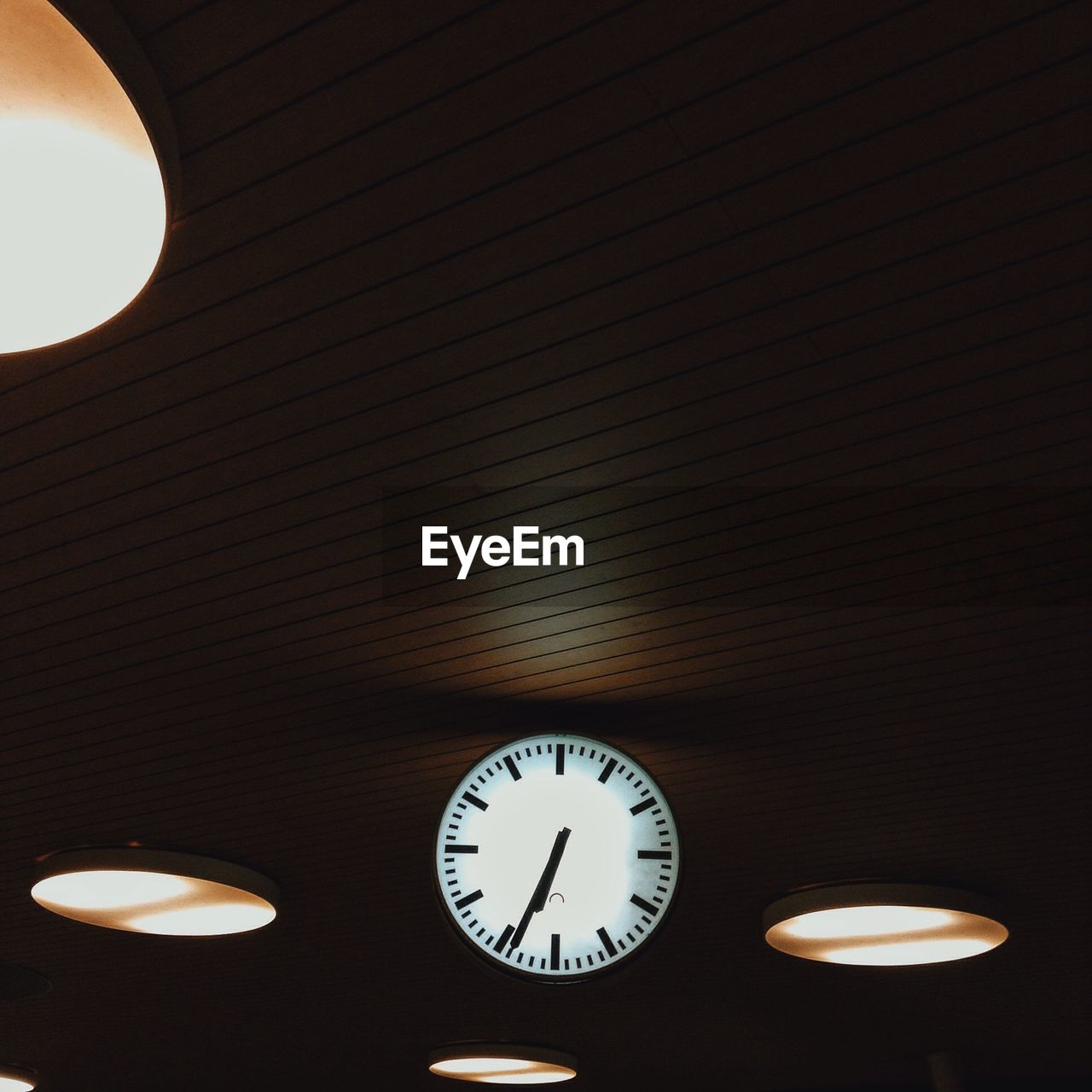Low angle view of clock on illuminated wall