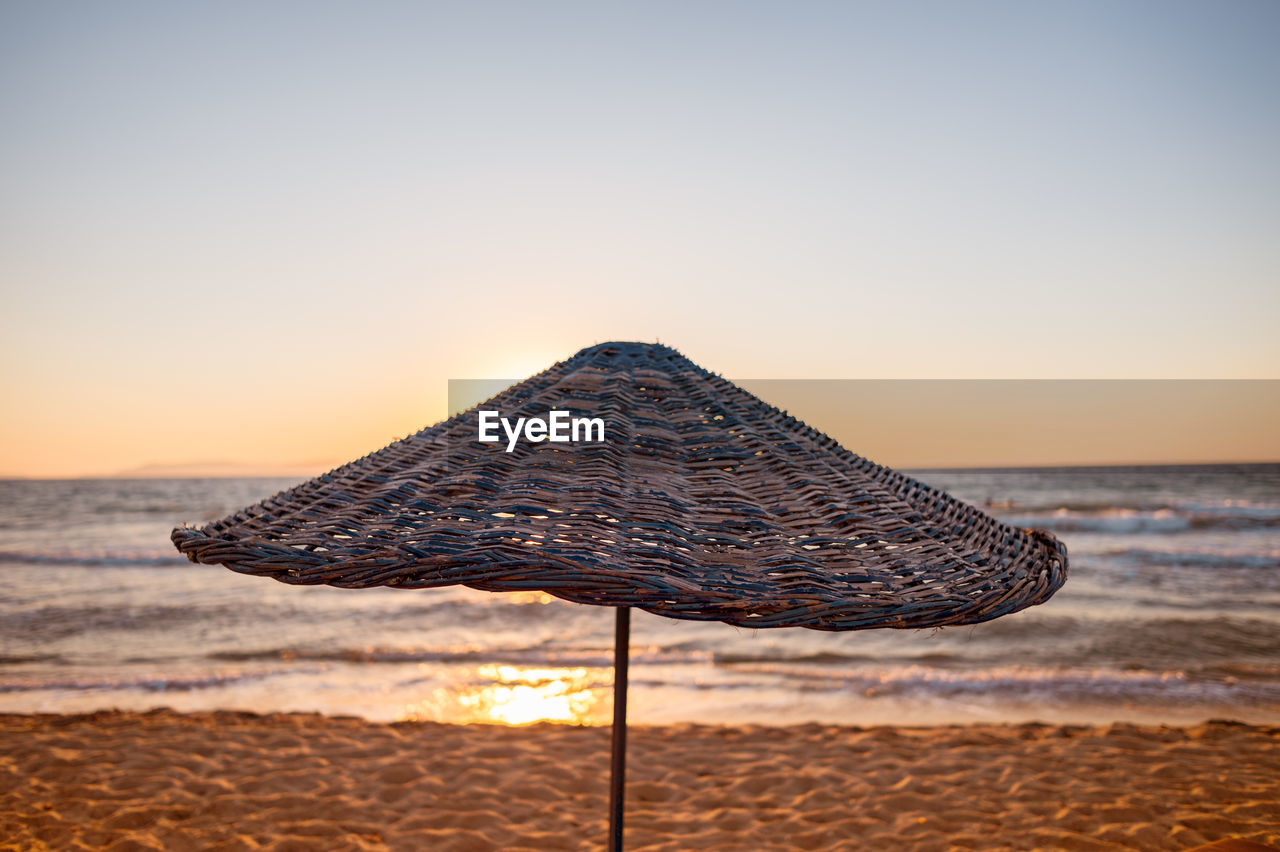 Parasol at beach against clear sky during sunset