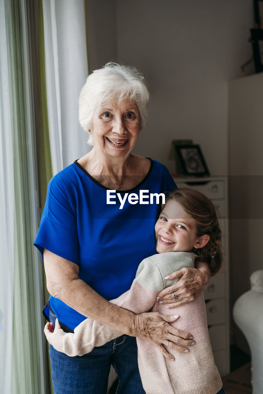 Happy girl embracing grandmother at home