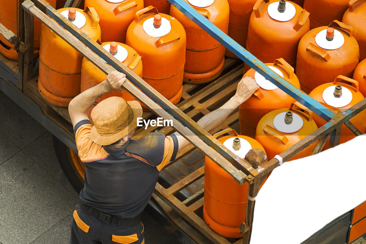 High angle view of man picking lpg cylinder from truck