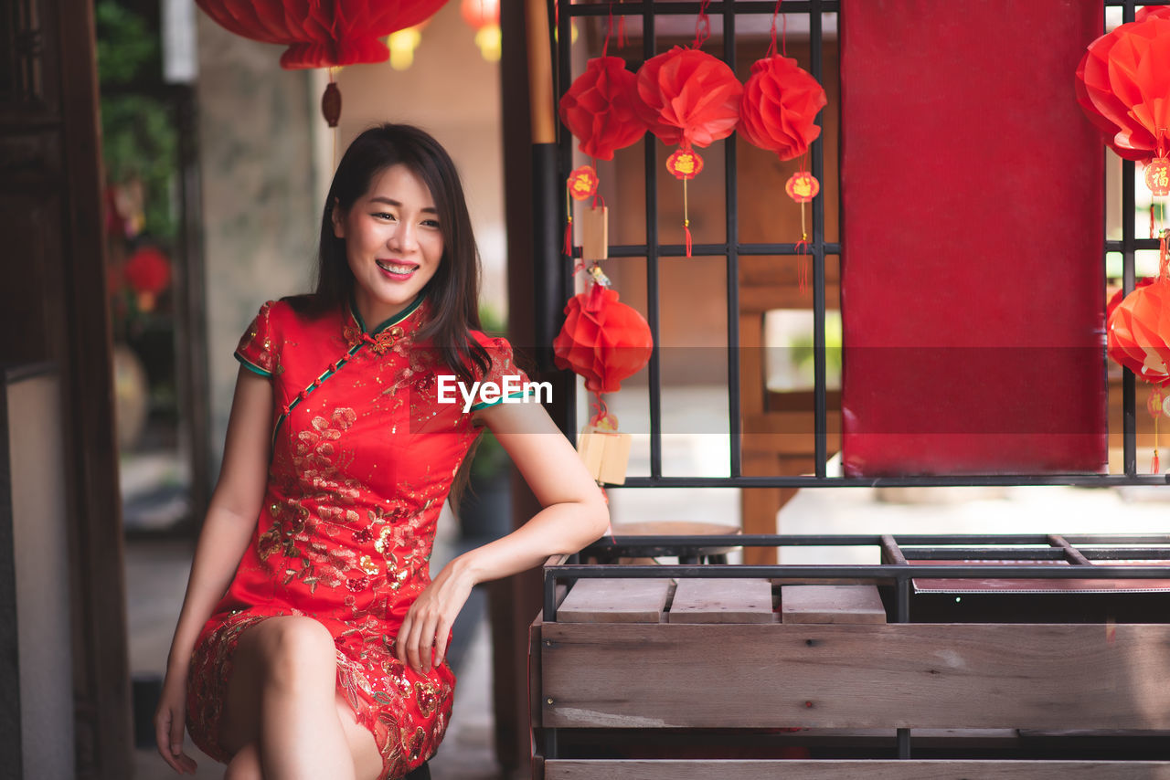 Smiling woman wearing red dress sitting outdoors