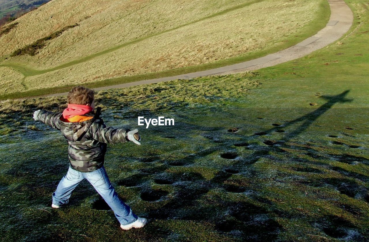 Rear view full length of boy with arms outstretched at malvern hills