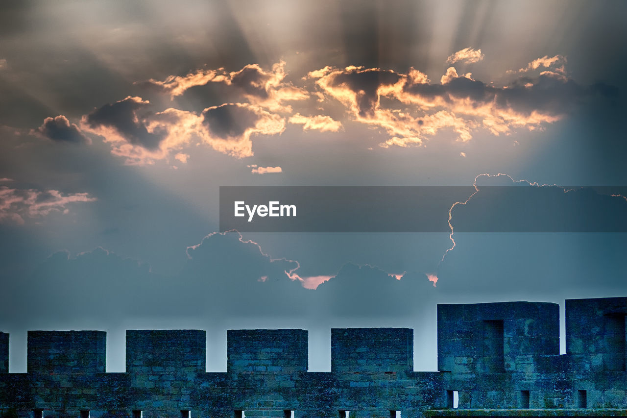 Low angle view of surrounding wall against back lit sky