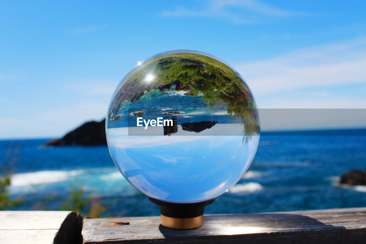 CLOSE-UP OF CRYSTAL BALL IN SEA AGAINST SKY