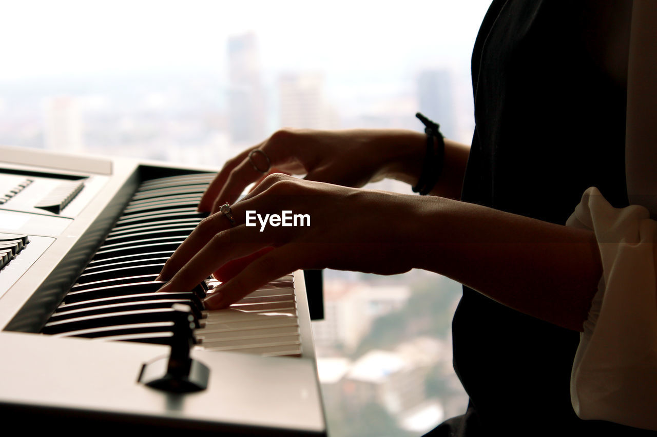 Close-up of midsection of woman playing synthesizer