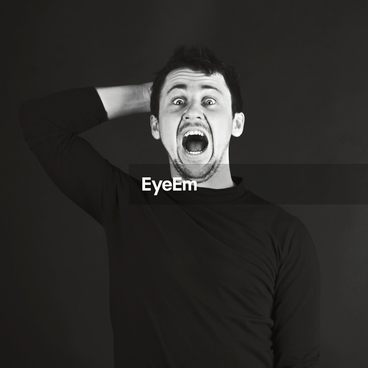 Portrait of man shouting while standing against black background