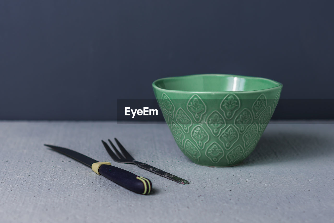 Close-up of knife and fork with bowl on table